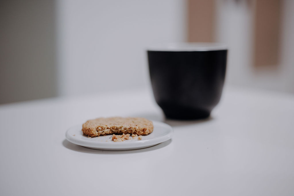Tasse mit angeknabbertem Keks auf Teller Stressmanagement Burnout Prävention