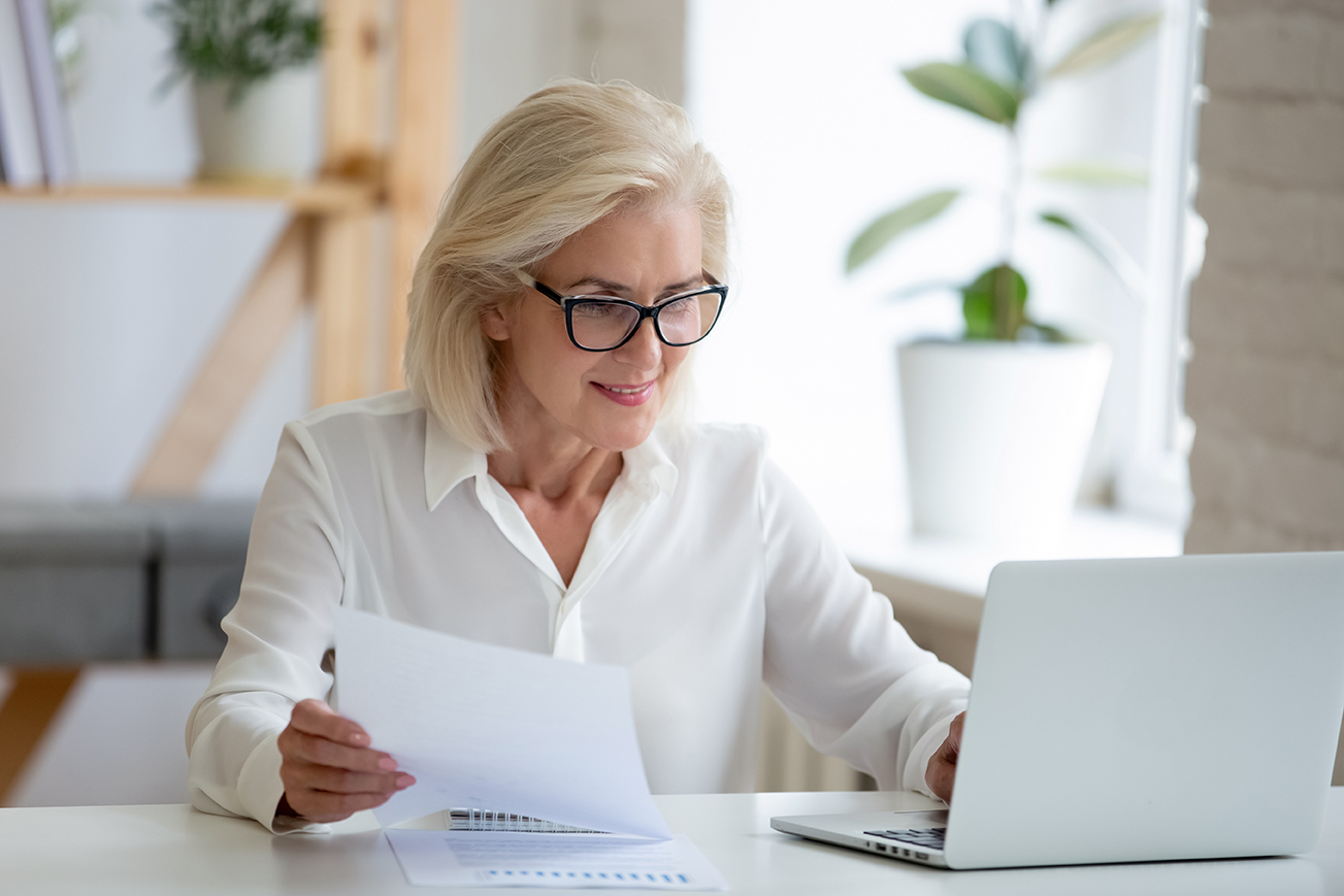 Aged,Businesswoman,Typing,On,Pc,Holds,Paper,Prepare,Report,Analyzing